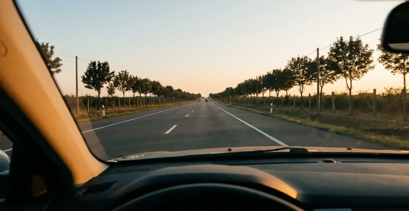 Vue depuis l'habitacle d'une voiture montrant une route dégagée s'étendant au loin avec des éléments de signalisation