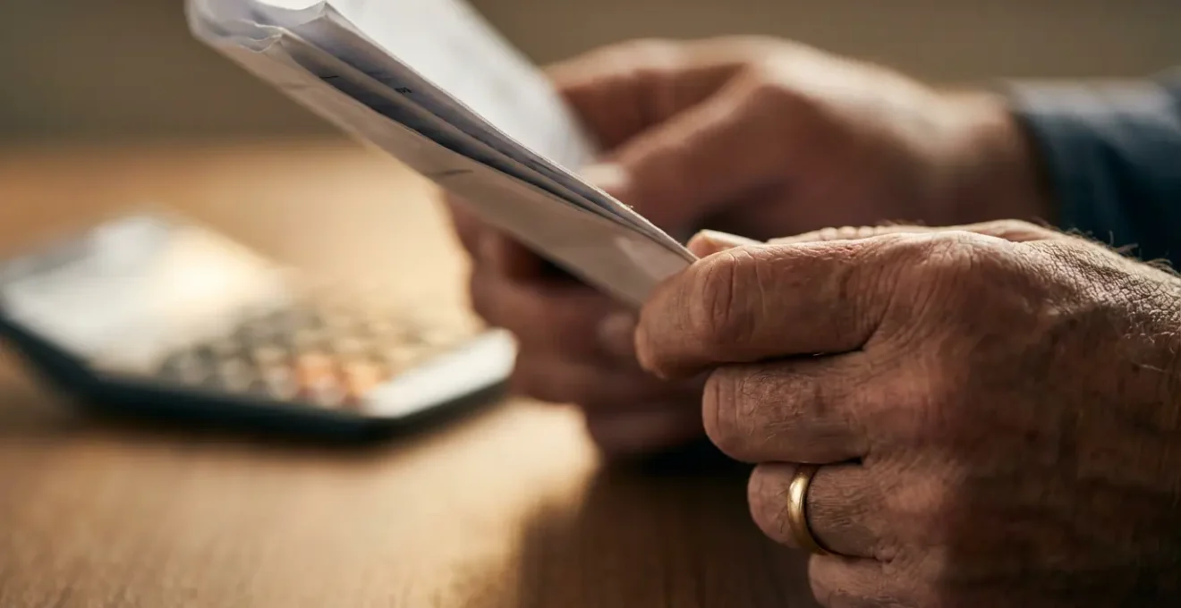 Personne stressée examinant des documents financiers avec une calculatrice